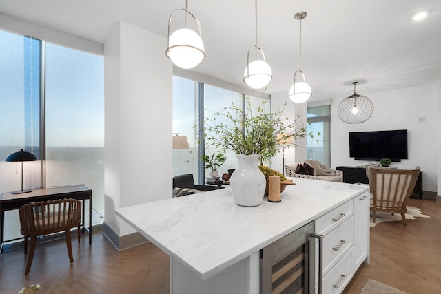 kitchen with a kitchen island, dark parquet floors, white cabinetry, beverage cooler, and hanging light fixtures