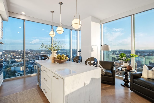 kitchen with white cabinetry, expansive windows, decorative light fixtures, and a wealth of natural light