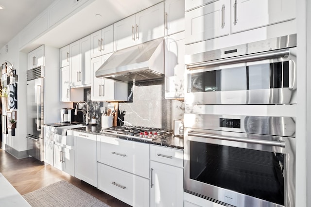 kitchen with stainless steel appliances, white cabinetry, and decorative backsplash