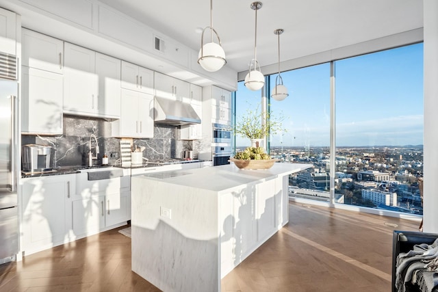 kitchen featuring a kitchen island, dark hardwood / wood-style floors, tasteful backsplash, white cabinets, and hanging light fixtures