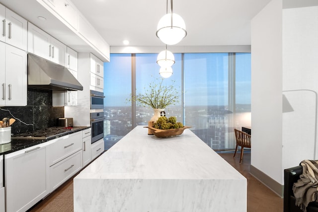 kitchen featuring a center island, hanging light fixtures, stainless steel appliances, decorative backsplash, and white cabinets