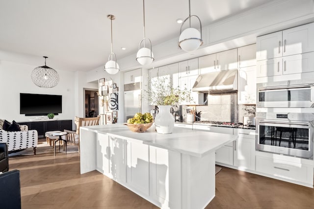 kitchen featuring pendant lighting, appliances with stainless steel finishes, white cabinetry, a center island, and tasteful backsplash