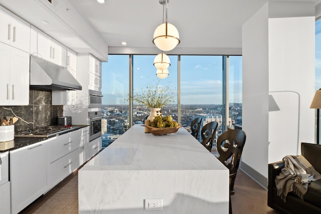 kitchen featuring stainless steel gas stovetop, white cabinetry, tasteful backsplash, hanging light fixtures, and a center island