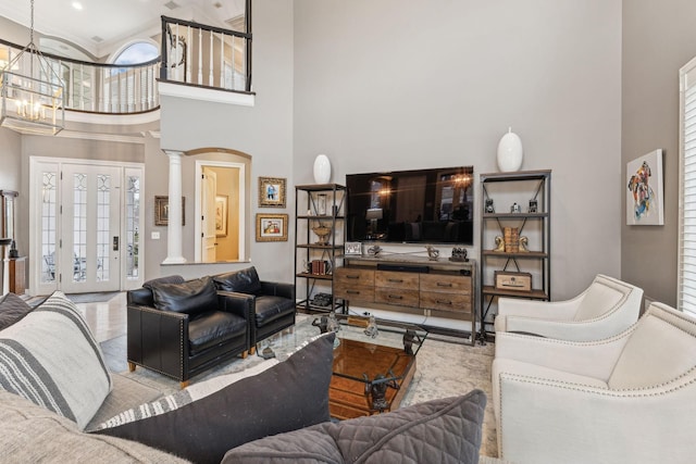 living room with decorative columns, a high ceiling, and an inviting chandelier