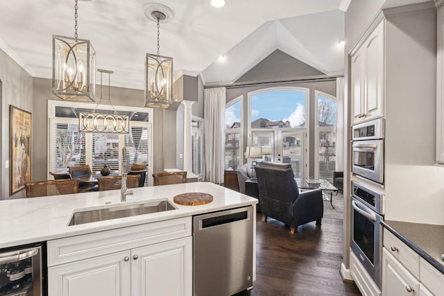 kitchen with sink, appliances with stainless steel finishes, white cabinetry, wine cooler, and decorative light fixtures