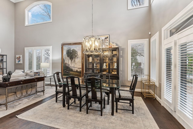 dining area with an inviting chandelier, wood-type flooring, and a high ceiling