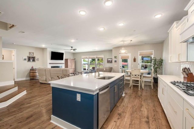 kitchen with sink, white cabinetry, appliances with stainless steel finishes, dark hardwood / wood-style floors, and a kitchen island with sink