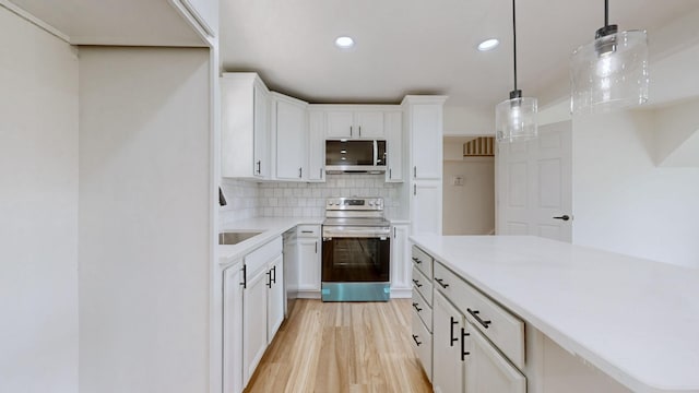 kitchen featuring pendant lighting, white cabinetry, appliances with stainless steel finishes, and light wood-type flooring