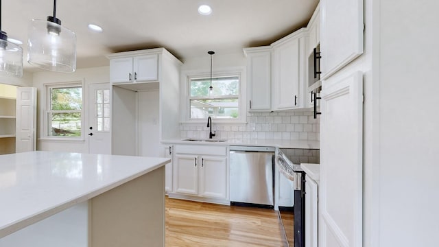 kitchen featuring dishwasher, sink, hanging light fixtures, and white cabinets