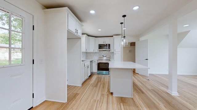 kitchen featuring stainless steel appliances, a center island, tasteful backsplash, white cabinets, and decorative light fixtures