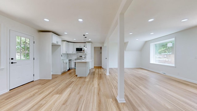 kitchen featuring appliances with stainless steel finishes, a kitchen island, decorative light fixtures, white cabinets, and decorative backsplash