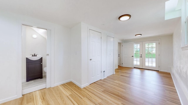 foyer featuring sink, light wood-type flooring, and french doors