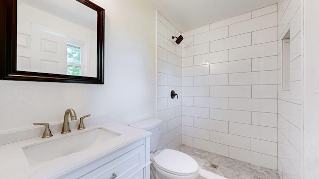 bathroom with vanity, toilet, and a tile shower