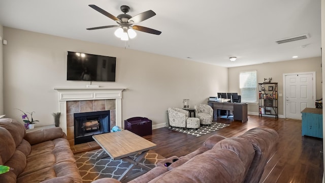 living room with ceiling fan, dark hardwood / wood-style flooring, and a tiled fireplace