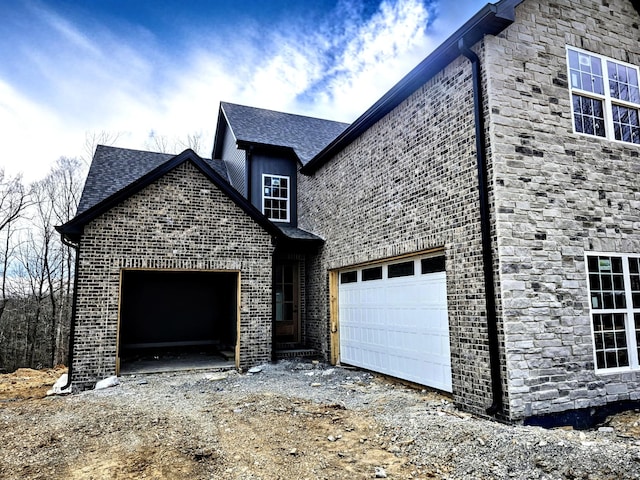 view of front of house with a garage, stone siding, brick siding, and dirt driveway