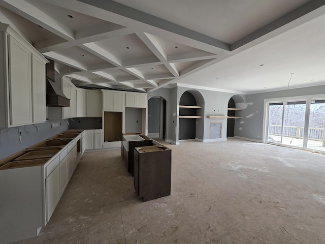 kitchen featuring arched walkways, beam ceiling, white cabinets, wall chimney range hood, and coffered ceiling