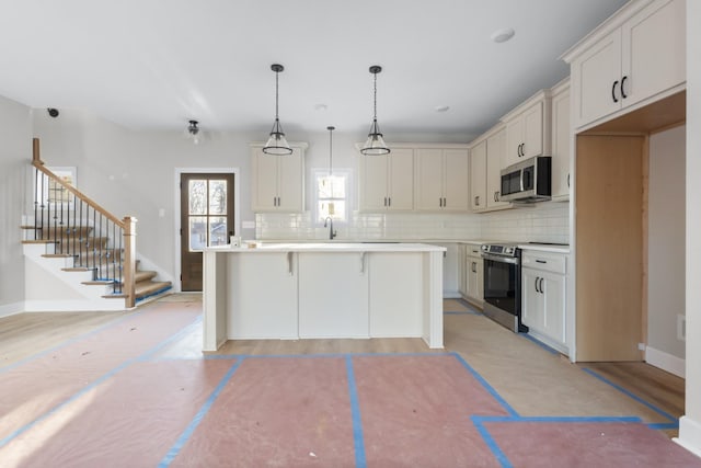 kitchen with a breakfast bar area, stainless steel appliances, light countertops, decorative backsplash, and a kitchen island