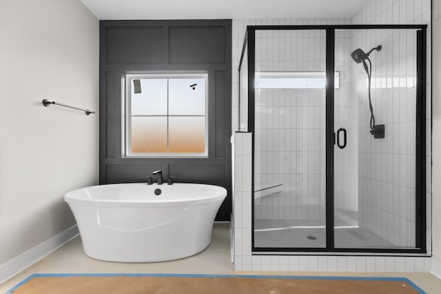 full bathroom with a freestanding tub, a shower stall, and baseboards