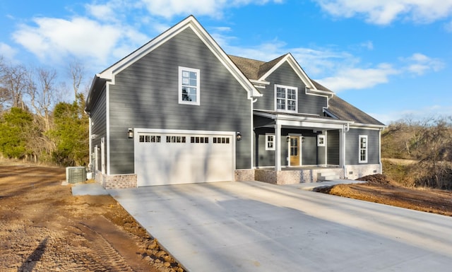 view of front facade with a porch, a garage, central AC, brick siding, and driveway