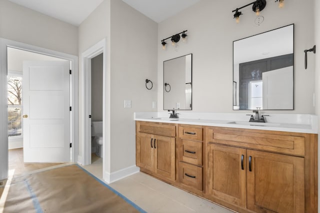 bathroom with double vanity, a sink, toilet, and tile patterned floors