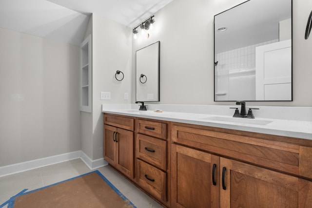 bathroom with double vanity, a sink, and baseboards