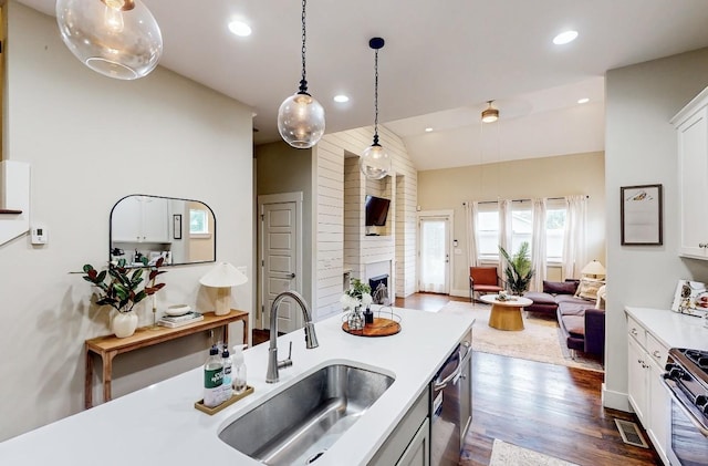 kitchen featuring sink, appliances with stainless steel finishes, hanging light fixtures, a fireplace, and white cabinets