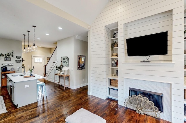 living room featuring a fireplace, sink, dark hardwood / wood-style floors, and vaulted ceiling