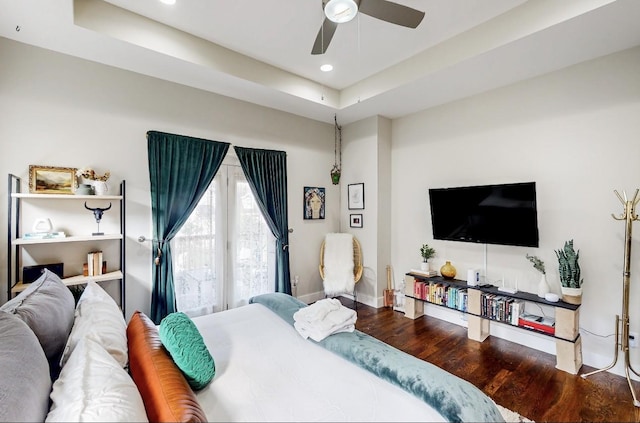 bedroom featuring a tray ceiling, wood-type flooring, and ceiling fan