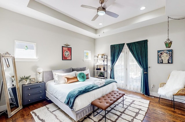 bedroom featuring dark wood-type flooring, ceiling fan, a tray ceiling, and access to exterior