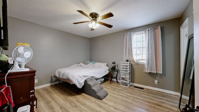 bedroom featuring ceiling fan, a textured ceiling, and light wood-type flooring