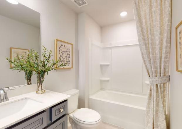 full bathroom with vanity, shower / tub combo with curtain, and toilet