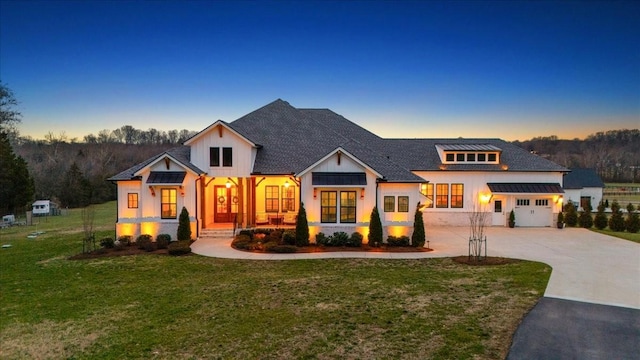 modern farmhouse with concrete driveway, a standing seam roof, and a front yard