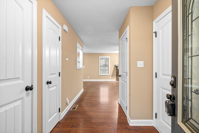 corridor featuring a textured ceiling and dark hardwood / wood-style flooring