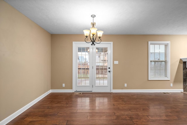 unfurnished dining area with a textured ceiling, dark hardwood / wood-style floors, and a chandelier