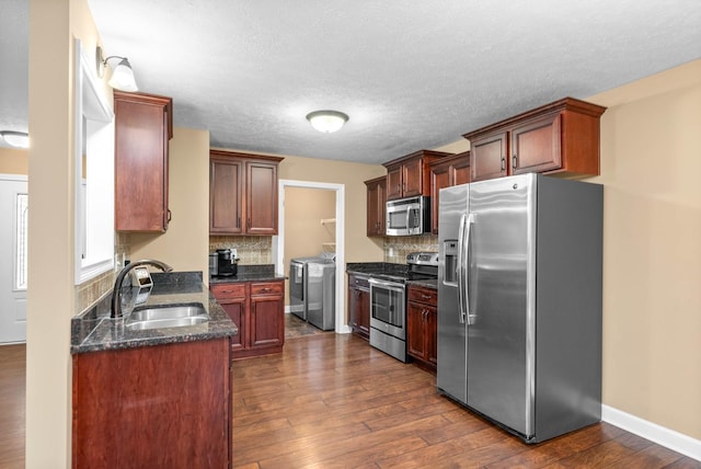 kitchen featuring appliances with stainless steel finishes, washer and dryer, sink, and dark hardwood / wood-style flooring