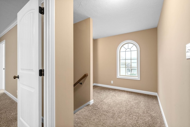 corridor with light colored carpet and a textured ceiling