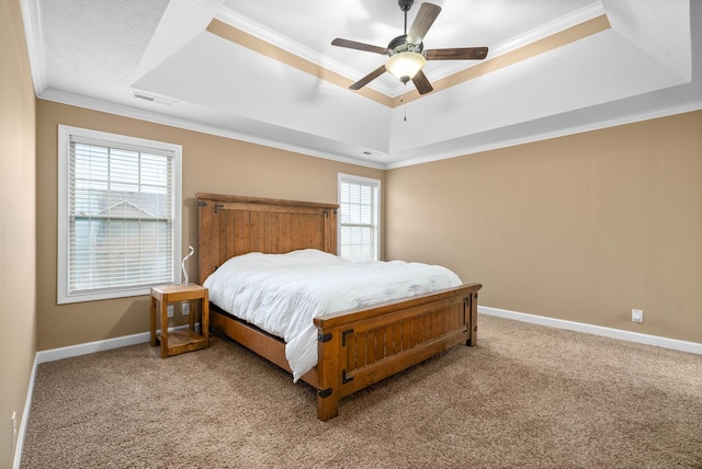 carpeted bedroom with crown molding, a tray ceiling, and ceiling fan