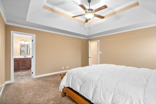 carpeted bedroom with crown molding, ensuite bath, a raised ceiling, and ceiling fan