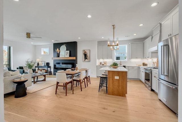 kitchen with high end appliances, white cabinetry, hanging light fixtures, and a kitchen island