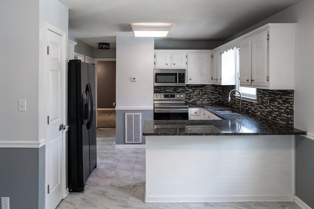 kitchen with sink, white cabinetry, stainless steel appliances, decorative backsplash, and kitchen peninsula