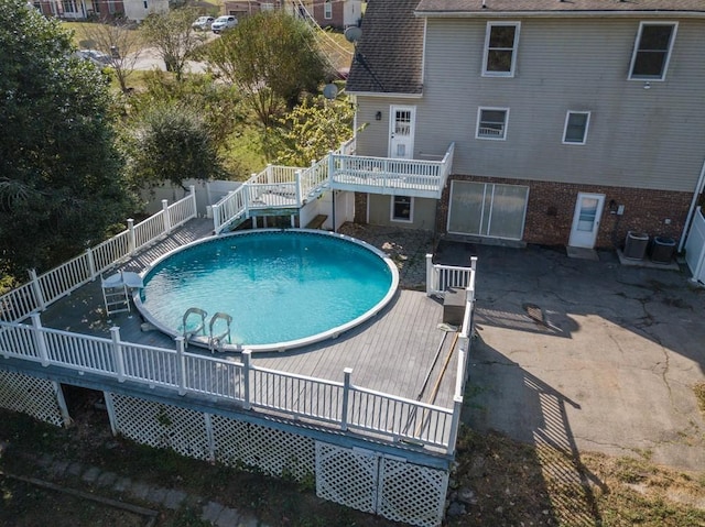 view of pool with central AC unit and a deck