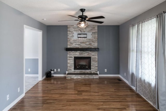 unfurnished living room with ceiling fan, dark wood-type flooring, a fireplace, and a textured ceiling