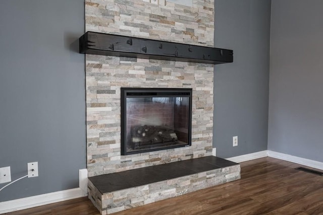 interior details featuring hardwood / wood-style flooring and a stone fireplace