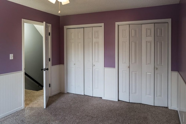 unfurnished bedroom with multiple closets, carpet flooring, and a textured ceiling