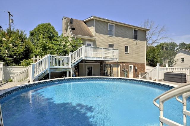 view of swimming pool featuring a wooden deck, fence, a fenced in pool, and stairway