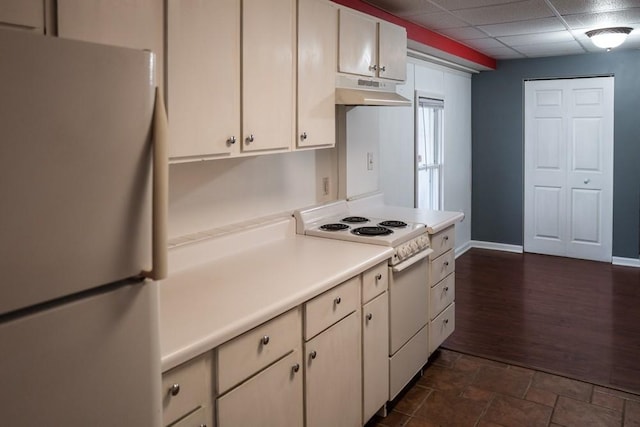 kitchen featuring a drop ceiling, white appliances, and white cabinetry