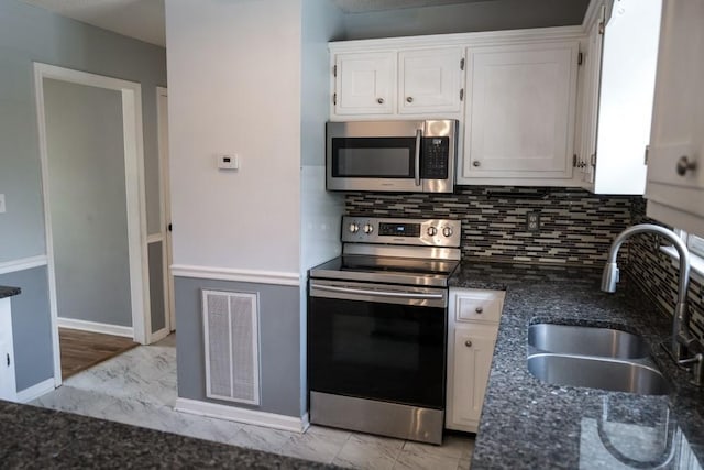 kitchen with sink, white cabinetry, dark stone countertops, appliances with stainless steel finishes, and decorative backsplash