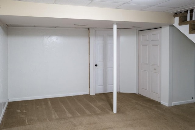 basement with a paneled ceiling and carpet