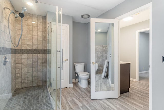 bathroom featuring a shower with door and toilet