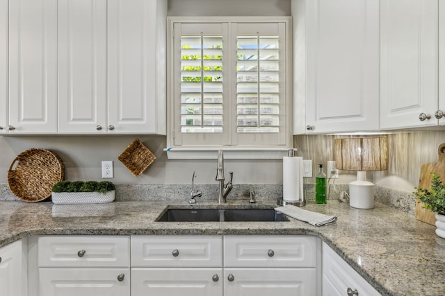 kitchen with white cabinetry, sink, and light stone counters